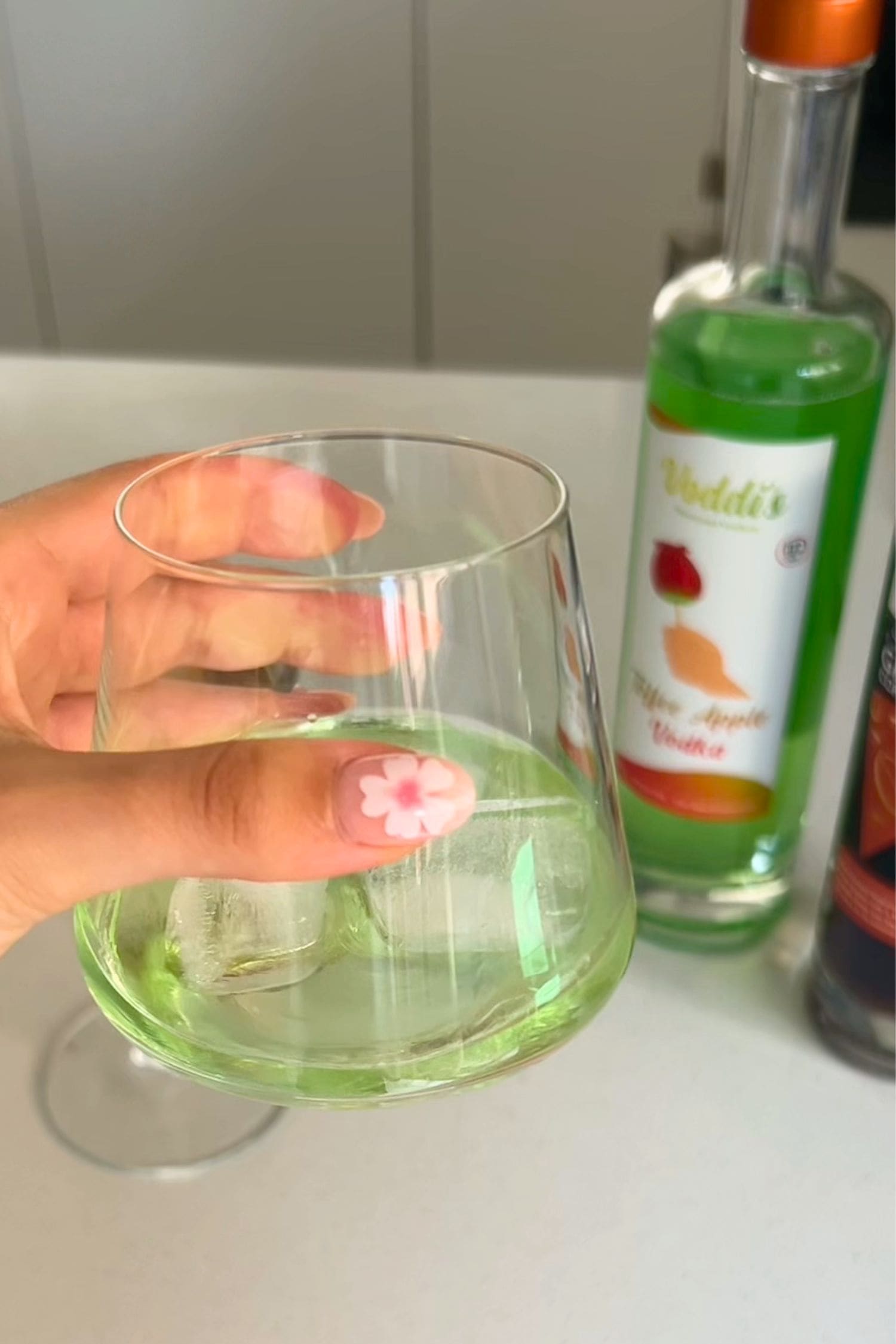 Voddi’s Toffee Apple Vodka served over ice in glass with bottle in background.