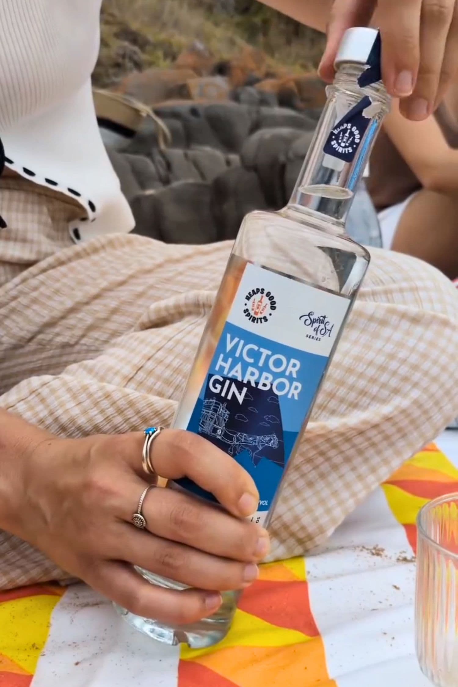 Hand holding Heaps Good Victor Harbor Gin during beach picnic in South Australia