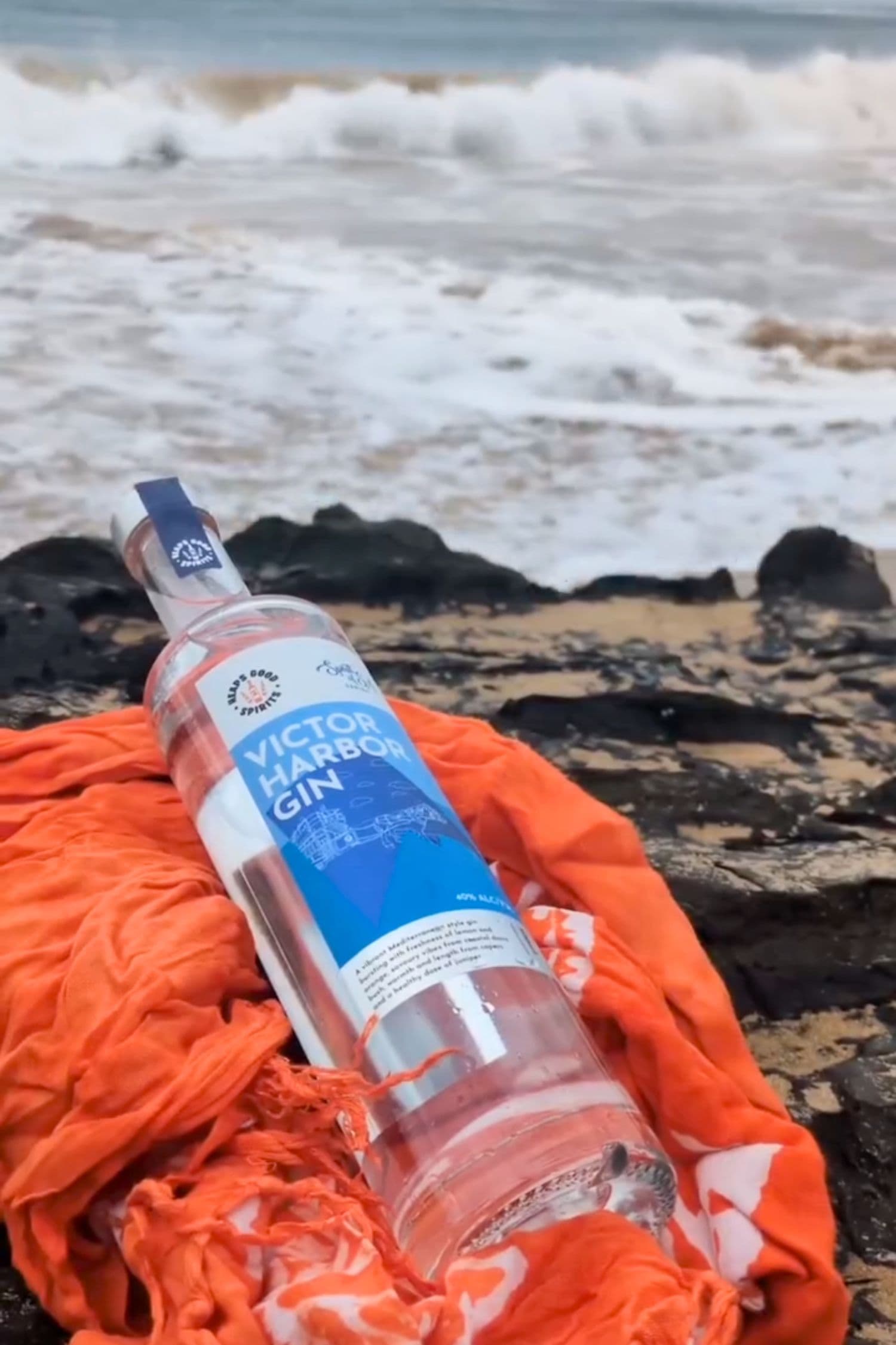 Victor Harbor Gin bottle on beach rocks with ocean waves in background