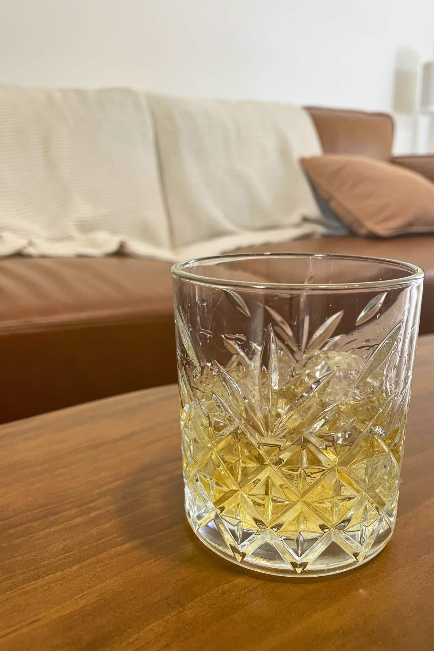 Heaps Good Spirits Whisky on the rocks in a relaxed home setting, with a couch in the background.